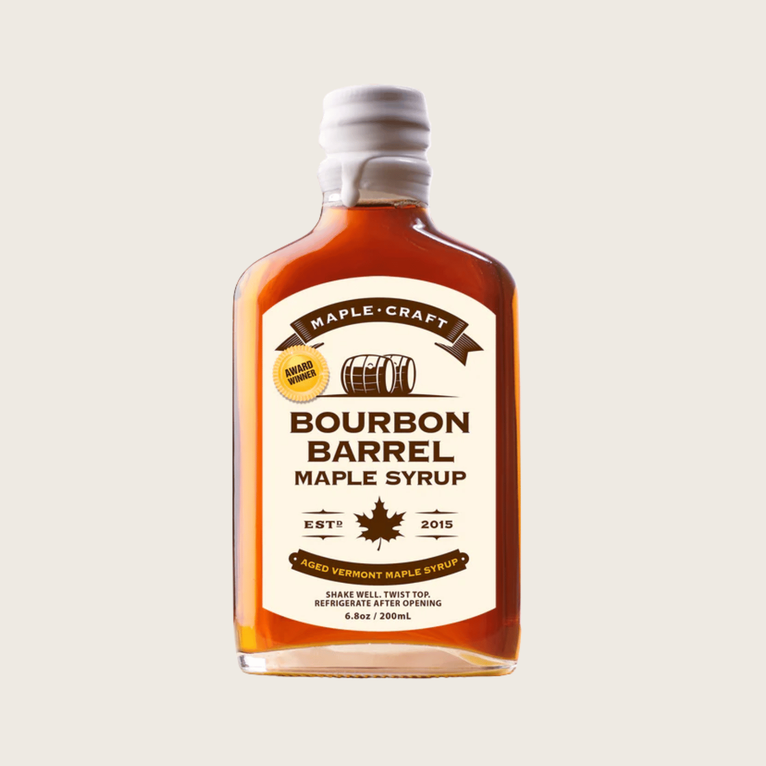 Bottle of Bourbon Barrel Maple Syrup with a white label on a beige background style=