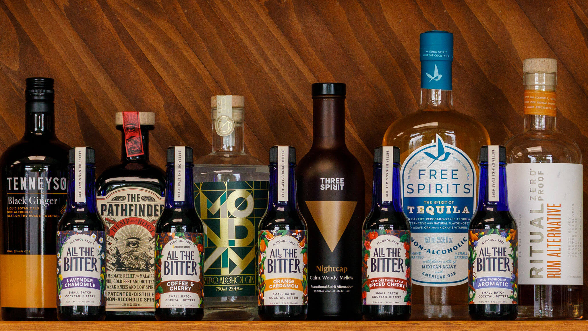 Non alcoholic spirits and bitters together on a shelf including All The Bitter, Pathfinder, and Three Spirit Nightcap.